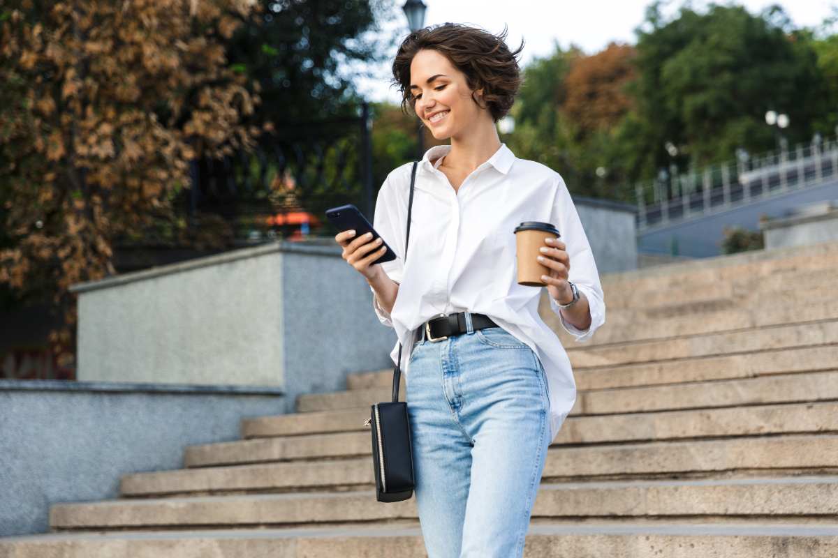 Ragazza scende scale con telefonino in mano